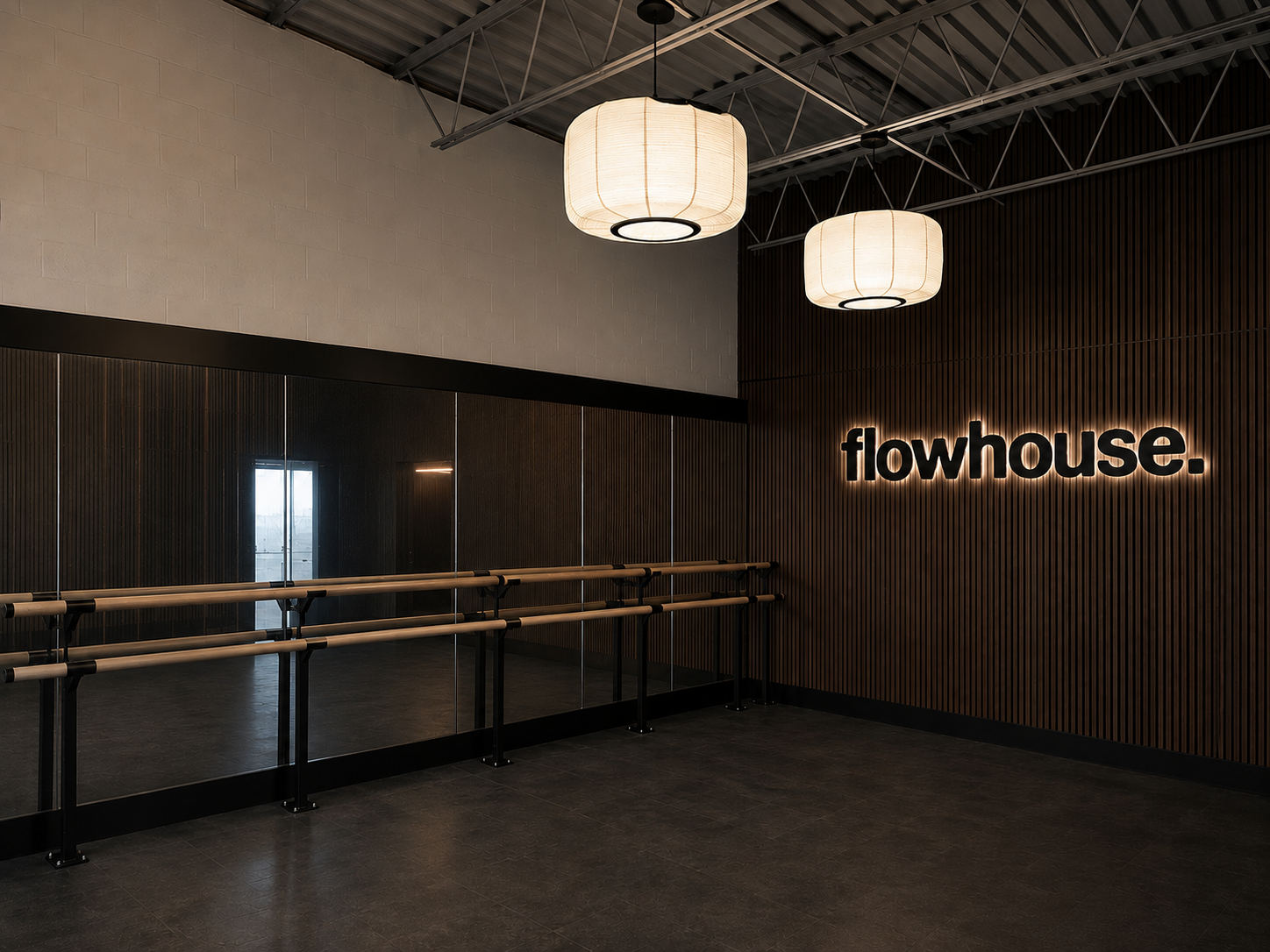 One of the two barre walls installed at flowhouse — wooden barre on black hardware against a glass partition