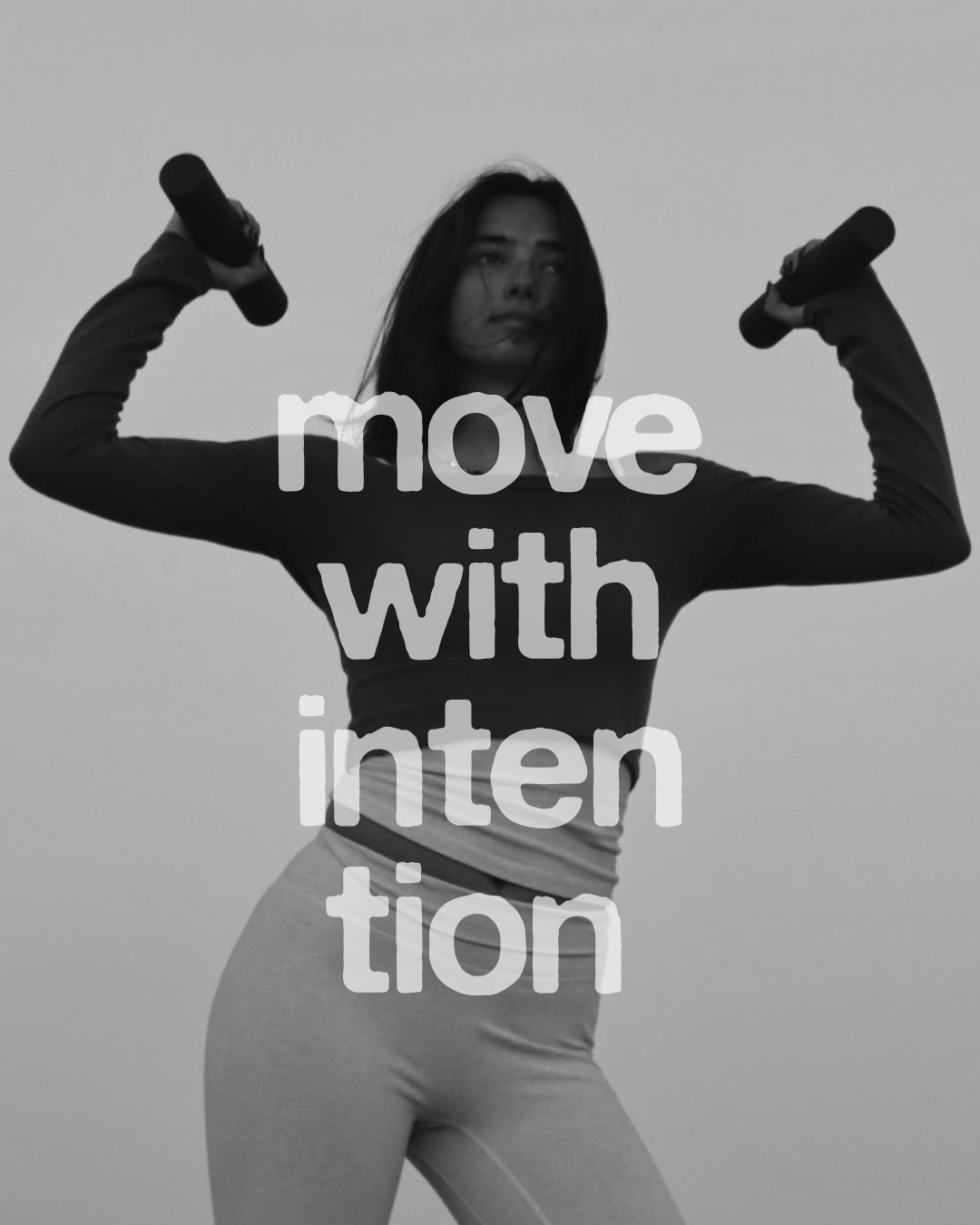 Sam, founder of flowhouse, in a black-and-white editorial portrait holding weights overhead.