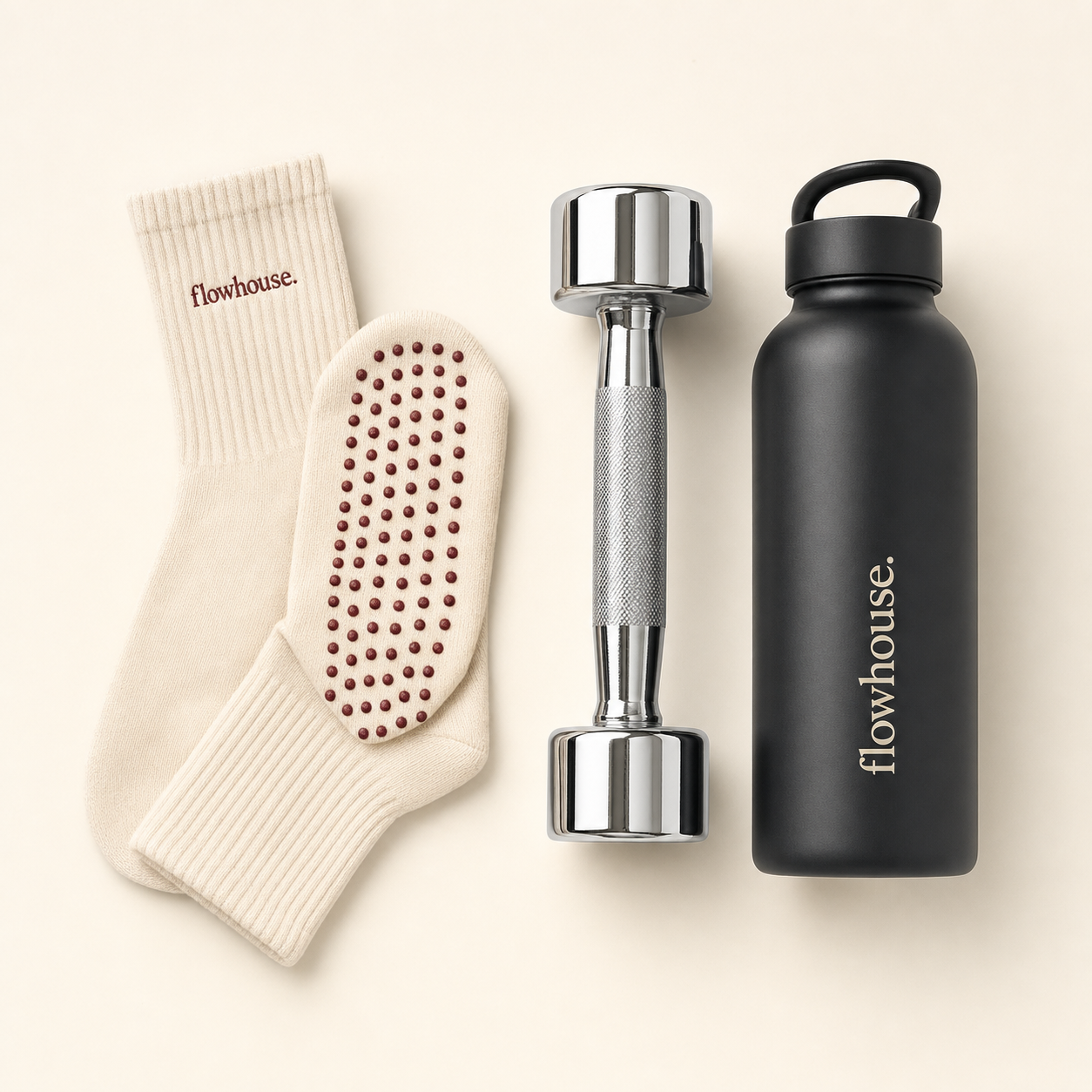 Flowhouse accessories — cream grip socks, chrome dumbbell, and matte-black water bottle on a cream backdrop.