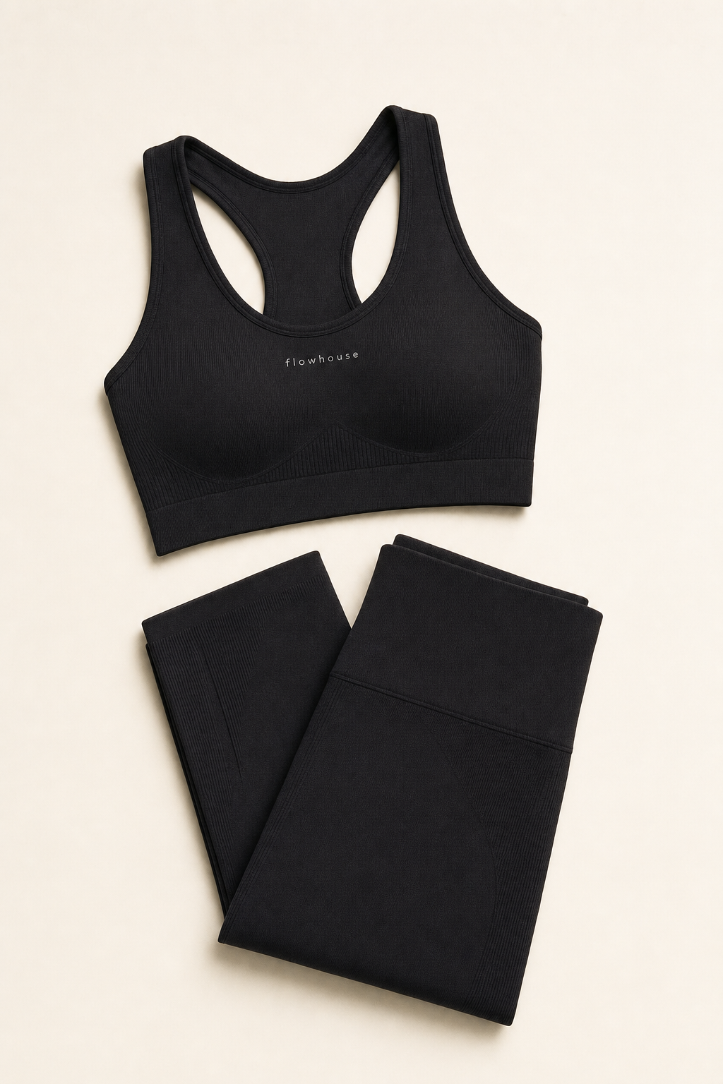 A folded flowhouse seamless sports bra and high-rise leggings flat-lay against a cream backdrop.