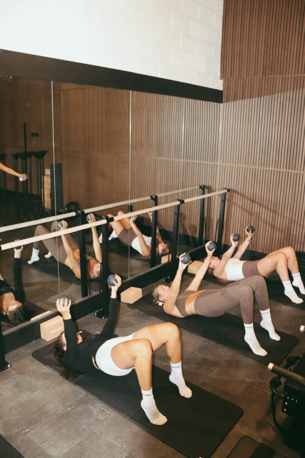 Members working the barre wall at flowhouse, wooden barre on minimal black hardware.
