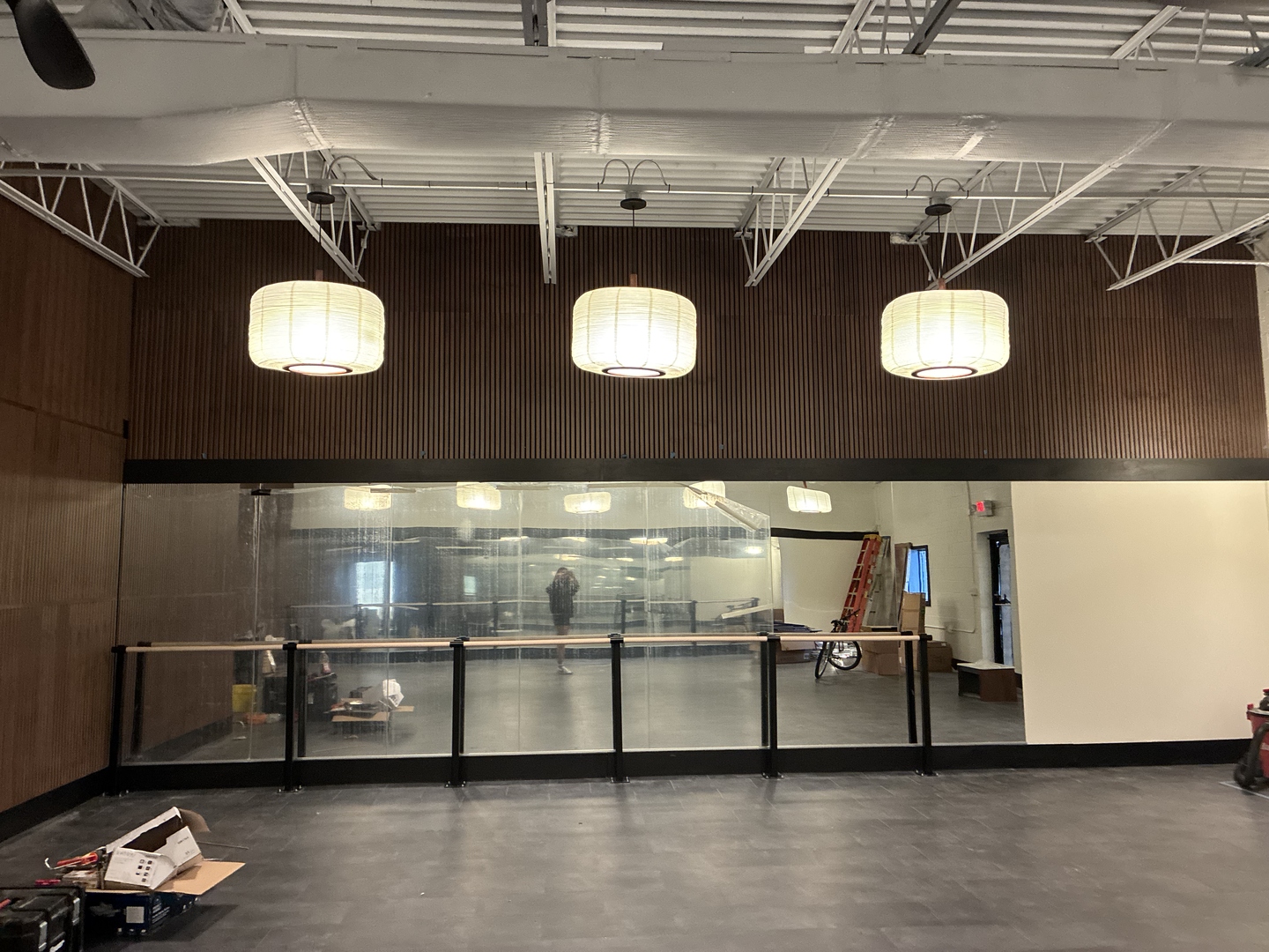 The flowhouse studio mid-build — wide view of the barre wall, three pendant lanterns, and walnut feature wall.
